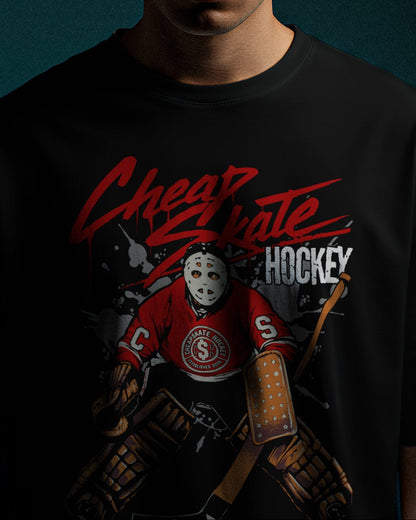 A man wearing a beige baseball cap and a black graphic t-shirt with a red and white hockey design, standing against a dark teal background.